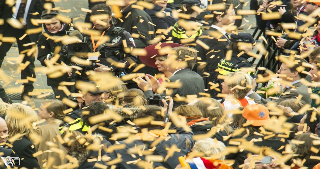 De koning en koningin omringd door oranje confetti